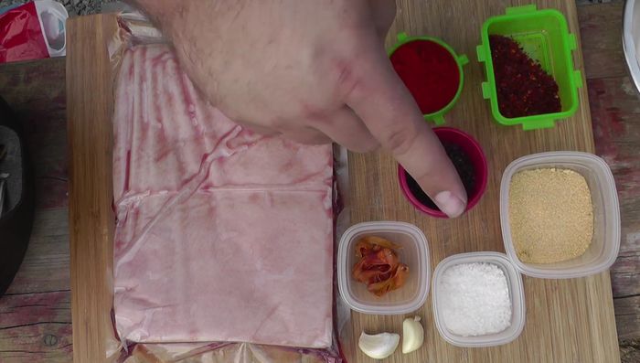 Schweinebauch vorbereiten: Sparte diagonal einritzen (108.78). Gewürzpaste herstellen: Knoblauch hacken, mit Salz, Zwiebelgranulat, Pfeffer, Chiliflocken, geräuchertem Paprikapulver und Muskatblüte vermischen (145.44). Mit Olivenöl vermengen (181.48).