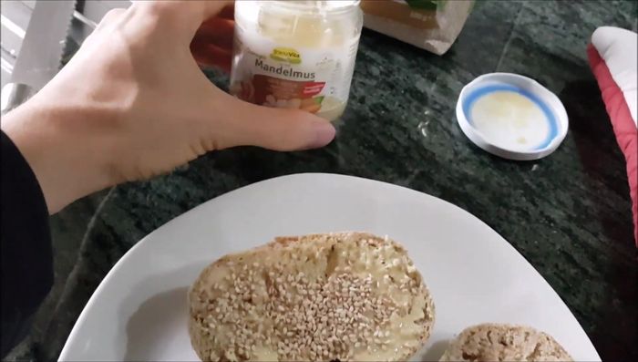 Mandelmus und Sesamsamen auf die fertig gebackenen Brötchen streichen.