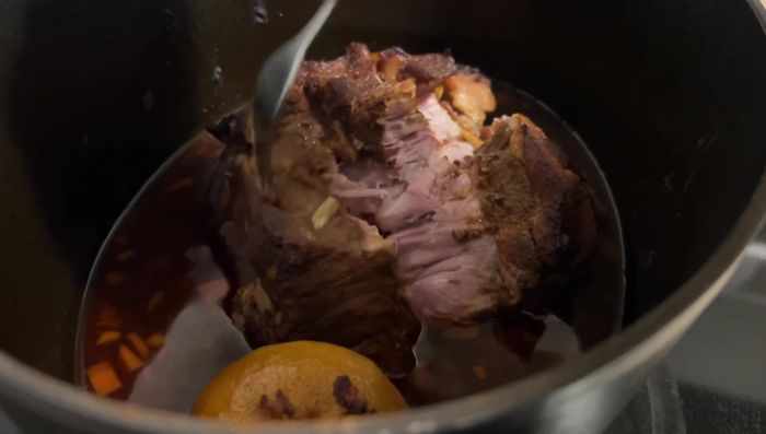 Nach 5 Stunden das Fleisch aus dem Topf nehmen und mit zwei Gabeln zerrupfen. Die Zitrone ausdrücken und den Saft zur Soße geben.