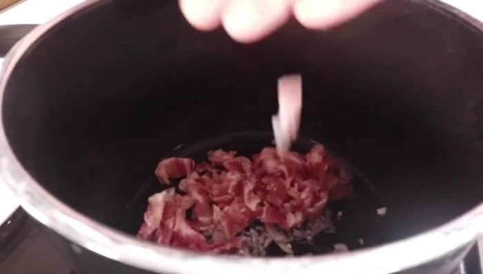 Schalotten und Speck in einem Topf anschwitzen, Knoblauch hinzufügen und mit Weißwein ablöschen. Mit Gemüsebrühe aufgießen und aufkochen.