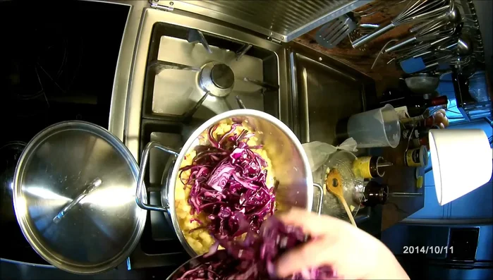 Marinierten Rotkohl, Rotwein, heißes Wasser, Brühe und Preiselbeeren zum Zwiebel-Apfelgemisch geben. Gut umrühren.