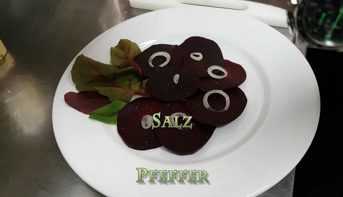 Zwiebelringe, geröstete Pinienkerne, etwas Ziegenkäse, Balsamico Essig und Öl darüber geben (213.93, 221.52, 232.53, 238.44). Mit Salz abschmecken (210.29).