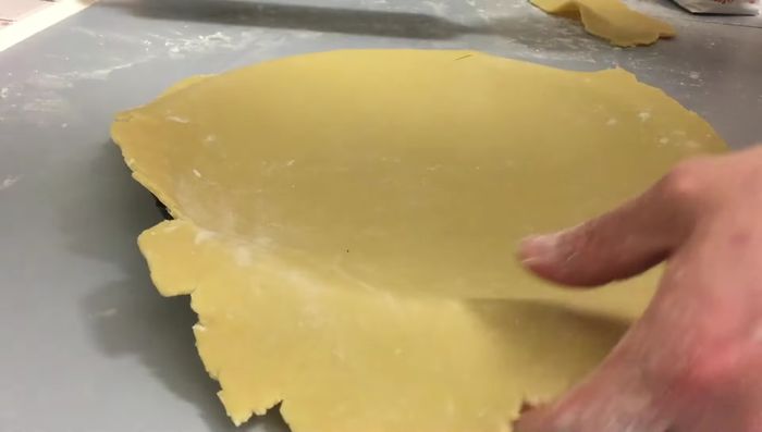 Blindbacken: Den Mürbeteig in die gefettete Form drücken. Mit Backpapier und Backgewicht (z.B. Linsen, Reis) belegen und 10 Minuten bei 180°C blind backen.