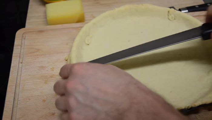 Füllung einfüllen: Nach dem Blindbacken die Füllung in den Teig geben und den Käse darüber reiben.