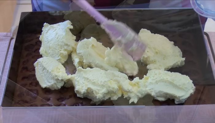 Buttercreme auf den abgekühlten Kuchen streichen und glatt streichen.