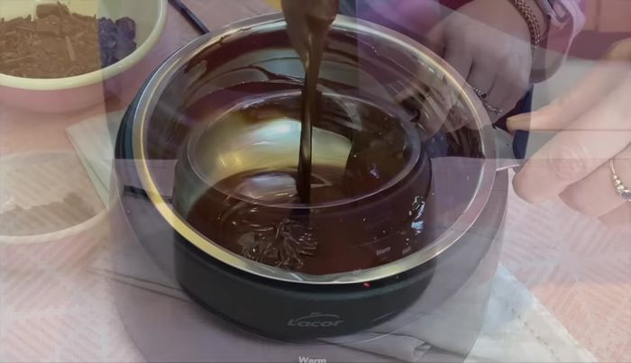 Schokoguss zubereiten: Kuvertüre schmelzen und mit Öl verrühren. Auf den Kuchen gießen und glatt streichen. Mit Kamm Wellenmuster ziehen (optional).
