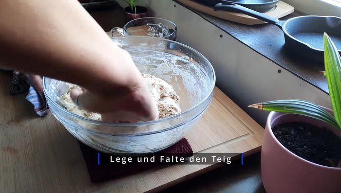 Hände befeuchten, Teig in eine bemehlte Form (gusseisener Topf oder Backform mit Backpapier/Mehl) geben und zu einer Kugel formen. Optional: Nochmals Röstzwiebeln oben drauf streuen.