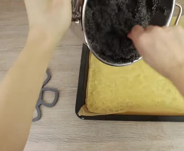 Mohnmasse gleichmäßig auf dem Teig verteilen.