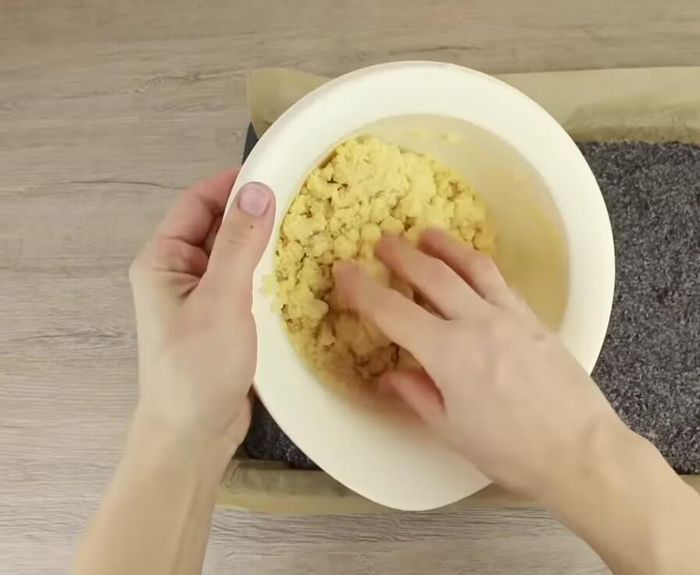 Restlichen Teig als Streusel auf der Mohnfüllung verteilen.