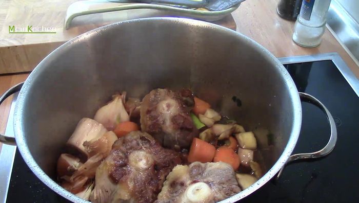 2 TL Gemüsegranulat, Lorbeer und Piment hinzufügen. Mit Wasser auffüllen, sodass der Ochsenschwanz bedeckt ist. Mit Deckel 3,5 Stunden köcheln lassen.