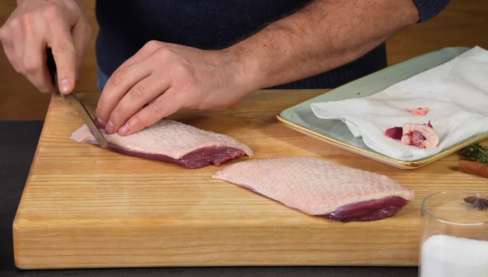 Entenbrust von überschüssigem Fett befreien und die Haut vorsichtig diagonal einschneiden (nicht ins Fleisch!).