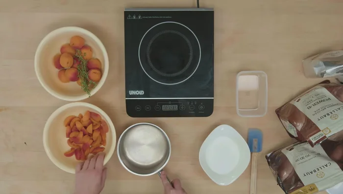 Aprikosen-Kern (Inlay) zubereiten: Zucker karamellisieren, mit Wasser ablöschen und Aprikosen darin weichköcheln lassen. In Silikonformen füllen und einfrieren.