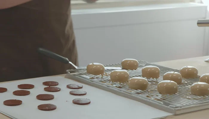 Törtchen zusammensetzen: Haselnuss-Mousse auf den Biskuitboden geben, Aprikosen-Kern daraufsetzen.