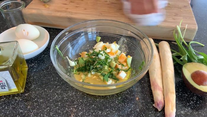 Spargel, Avocado, Ei und Bärlauch auf einem Teller anrichten.