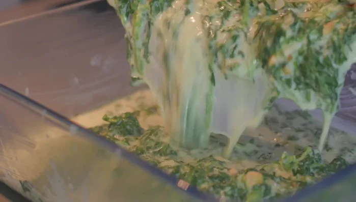 Spinatmasse in die Auflaufform geben, Kartoffeln darauf verteilen.