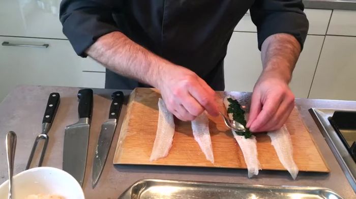 Seezungenröllchen formen: Verbreiten Sie den Spinat auf der Hautseite der Seezungenfilets. Geben Sie ein kleines Stück Lachsforelle in die Mitte. Rollen Sie die Filets vorsichtig auf.
