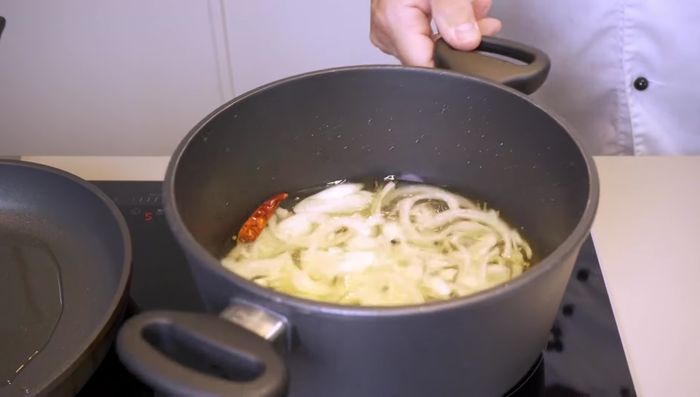 Zwiebeln zum kochenden Fond geben und kurz aufkochen lassen.