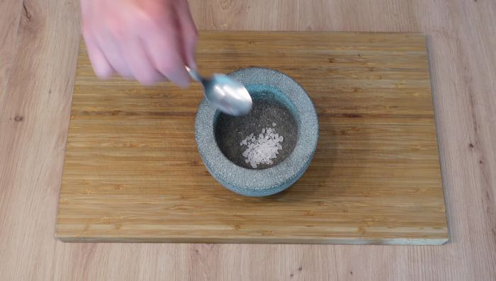 Gewürze im Mörser zerstoßen: Grobes Meersalz, schwarzen Pfeffer, Knoblauchpulver und edelsüßen Paprika vermengen.