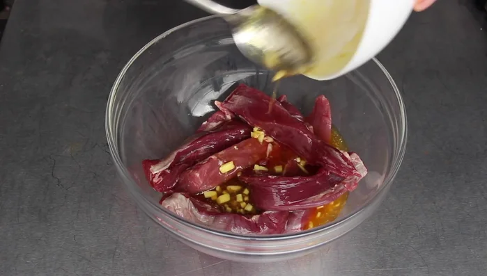 Die Marinade über das Lammfilet gießen und gut vermengen.