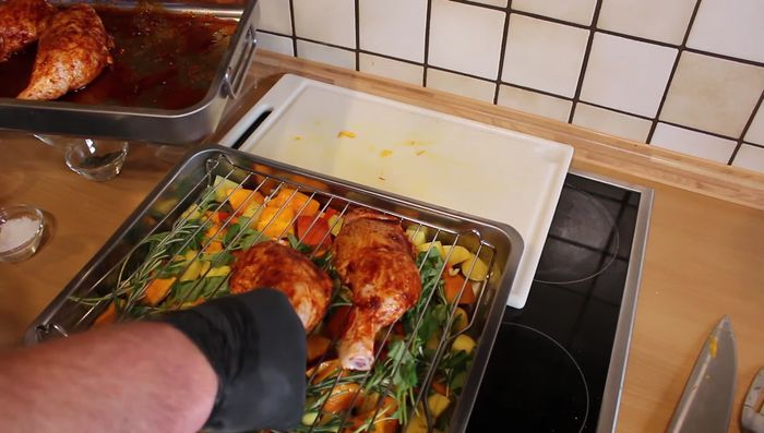 Hähnchenkeulen auf das Gemüse legen. Bei 190-200 Grad ca. 1 Stunde grillen.