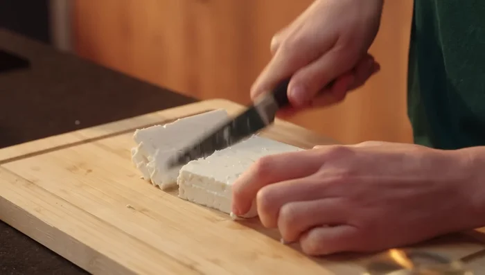200g Feta in Würfel schneiden und unter die Spinatmasse heben. Mit Muskat, Pfeffer und Salz abschmecken. Cheddar reiben.