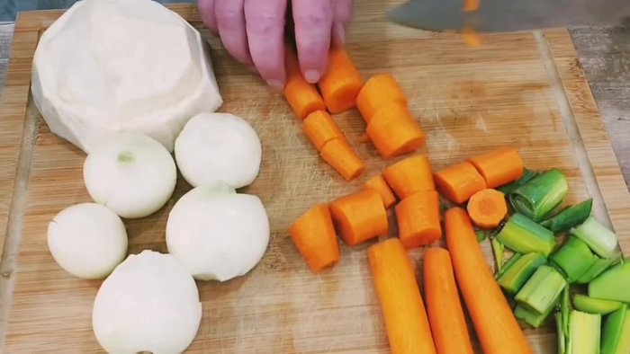 Gemüse (Porree, Zwiebeln, Möhren, Sellerie) grob hacken und in einen Topf geben. Haxe dazugeben und mit Wasser bedecken.