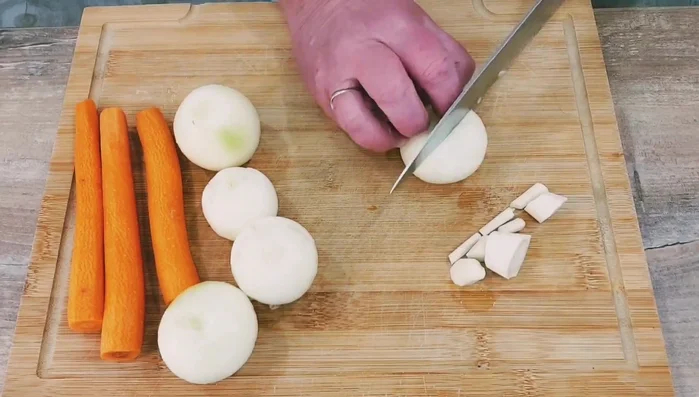 Gemüse für die Soße (Petersilienwurzel, Zwiebeln, Möhren) grob schneiden und in einen Bräter geben.