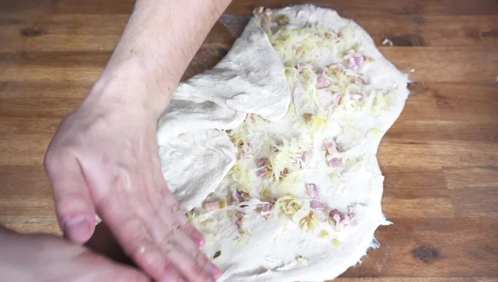 Teig vorsichtig einschlagen, dabei darauf achten, dass Speck, Sauerkraut und Zwiebeln gut eingearbeitet sind (264.54).