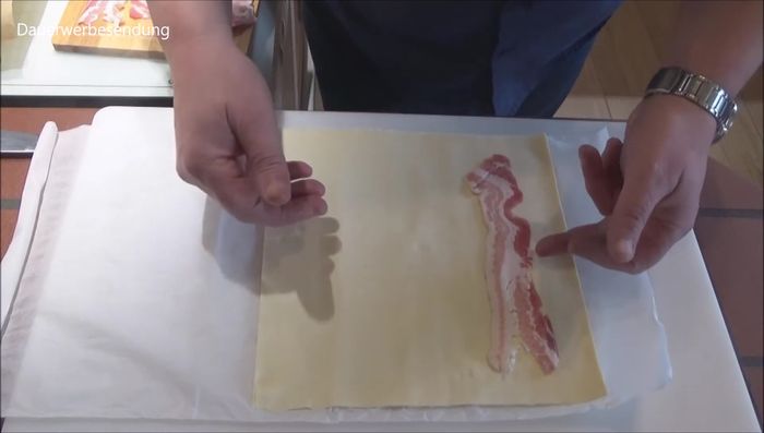 Füllung auf den Blätterteig geben: Abgekühltes Kalbsfilet auf den Blätterteig legen, mit der Füllung bedecken und mit Eigelb bestreichen (374.05).