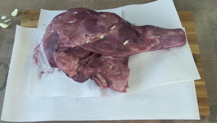 Lammschulter mit Olivenöl beträufeln. Knoblauch, pürierte Tomaten, Rosmarin, mediterrane Gewürzmischung, Salz und Pfeffer hinzufügen. Gut vermengen.