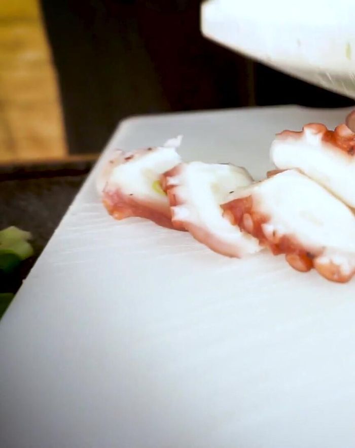 Oktopus in mundgerechte Stücke schneiden. Dabei auf eventuelle harte Stellen achten und diese fein schneiden (78.49).