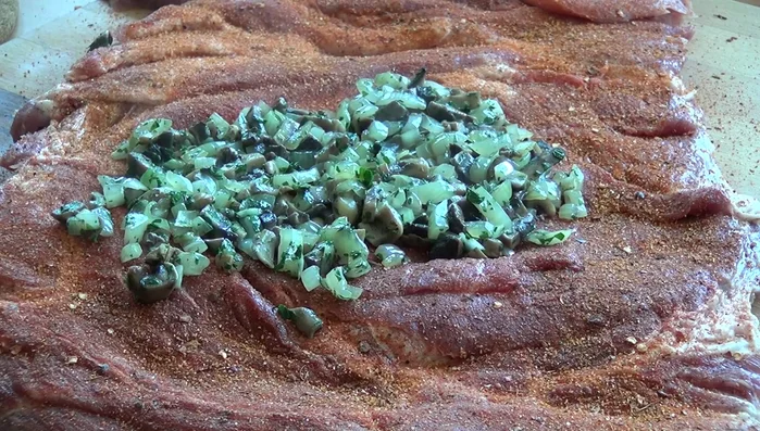 Abgekühlte Pilzmasse gleichmäßig auf dem Fleisch verteilen.