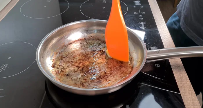 Bratensoße zubereiten: Butterschmalz in der Pfanne erhitzen. Zucker karamellisieren. Gehackte Zwiebel hinzufügen und ebenfalls karamellisieren.