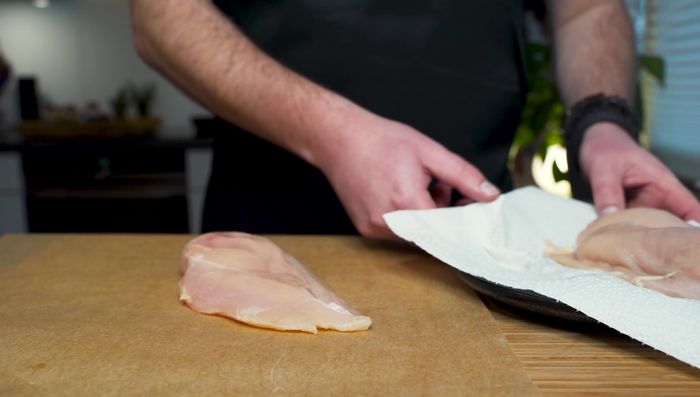 Hähnchenbrustfilet zwischen Backpapier legen und mit Salz und Pfeffer würzen. Mit einem Fleischklopfer (oder Nudelholz) leicht plattieren.