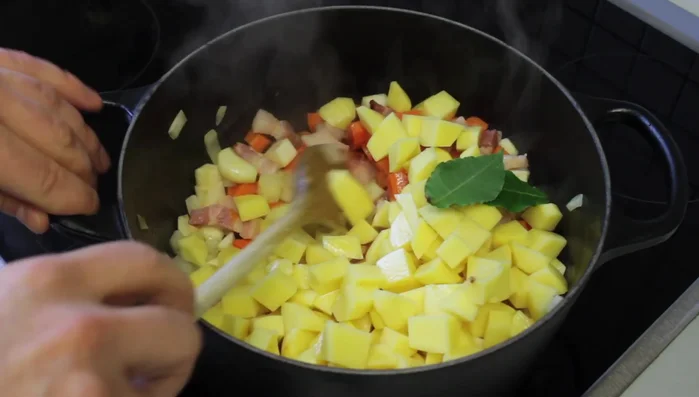 Lorbeerblätter, Linsen (vorher abgespült, optional über Nacht in Salzwasser eingeweicht), Pfeffer und optional Natron zum Gemüse geben. Mit Wasser auffüllen.