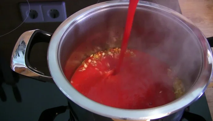 Passierte Tomaten zugeben, Deckel auflegen und zum Kochen bringen.