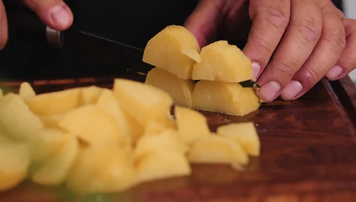 Kartoffelsalat vorbereiten: Pellkartoffeln kochen, abkühlen lassen und in Stücke schneiden.