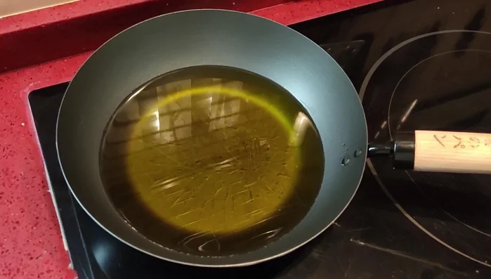 Olivenöl in einem Wok oder Topf erhitzen und die Auberginenstreifen goldbraun frittieren.