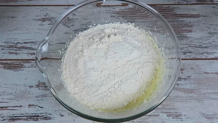 Mehl und Backpulver hinzufügen und gut verkneten, bis ein klebriger Teig entsteht.