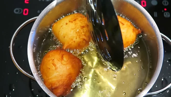 Frittierte Bällchen auf Küchenpapier legen, um überschüssiges Fett zu entfernen.