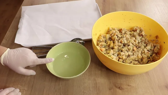 Mit einem Eisportionierer Knödel formen, in kaltem Wasser kurz befeuchten und gut festdrücken.