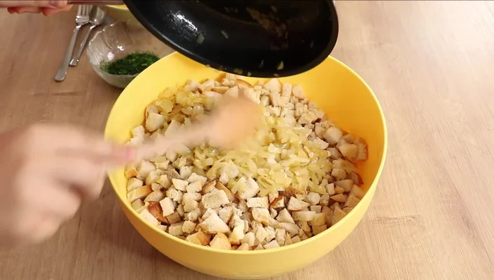 Erwärmte Milch-Butter-Mischung über die Semmelwürfel geben. Kräuter, Knoblauchpaste/Knoblauchzehen hinzufügen.