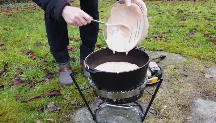 Soße in den Dutch Oven geben, aufkochen und mit Chili und Pfeffer würzen.