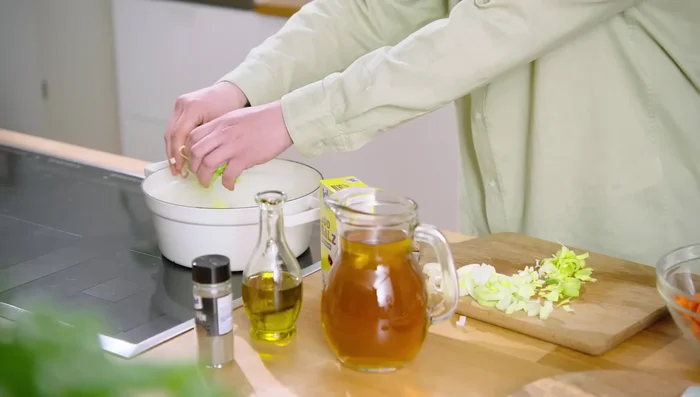 Öl im Topf erhitzen. Drei Viertel des Lauchs anbraten.