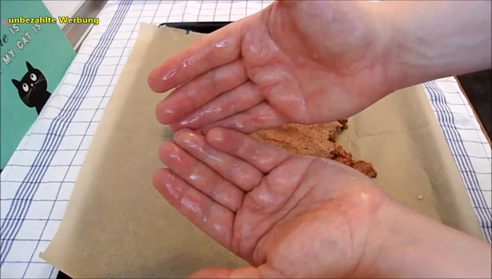 Teig auf ein mit Backpapier ausgelegtes Backblech geben und zu einem gleichmäßigen Quadrat formen.