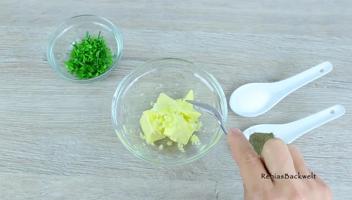 Knoblauchbutter zubereiten: Weiche Butter, Knoblauch, Schnittlauch, Salz und Pfeffer vermengen. (97.799)