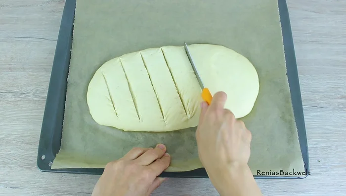 Teig mehrmals einschneiden, mit Knoblauchbutter bestreichen und Mozzarellastreifen in die Einschnitte füllen. (114.13)