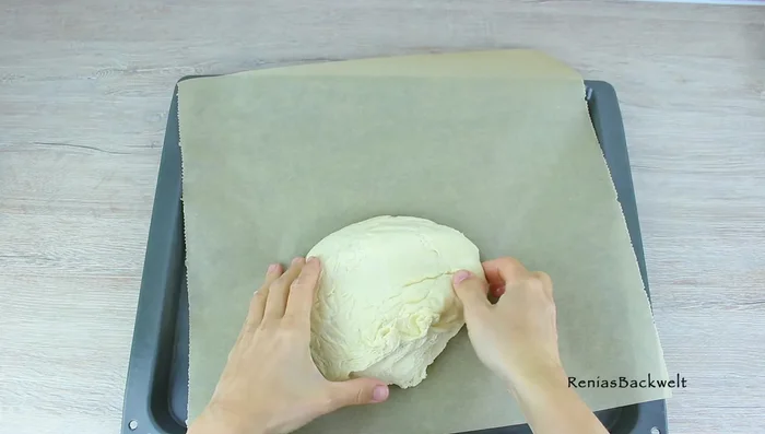 Teig auf ein mit Backpapier ausgelegtes Backblech legen und leicht andrücken. Mit einem Tuch abdecken und weitere 15 Minuten gehen lassen. (80.43)