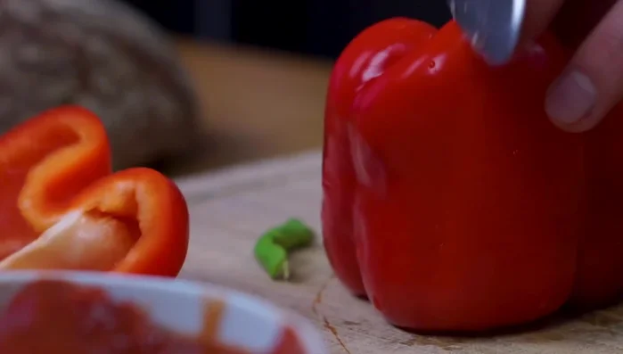 Paprika putzen, Strunk entfernen und in Streifen schneiden.