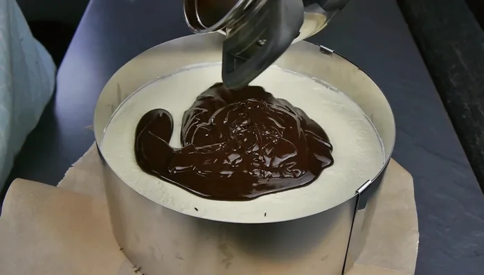 Weiße Schokolade schmelzen und auf die Torte spritzen. Muster mit Schaschlikspieß ziehen.